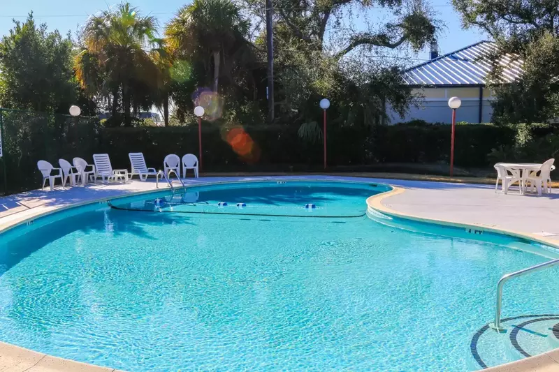 The Beachside community pool has a large sundeck with sun loungers, a dining table and chairs.