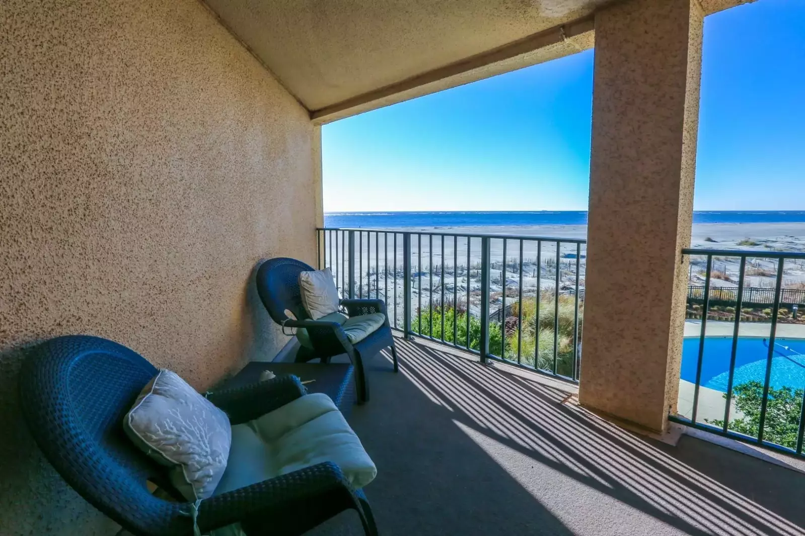 The private, covered balcony at Salty Sunrise overlooks the community pool, sand dunes and Atlantic ocean.