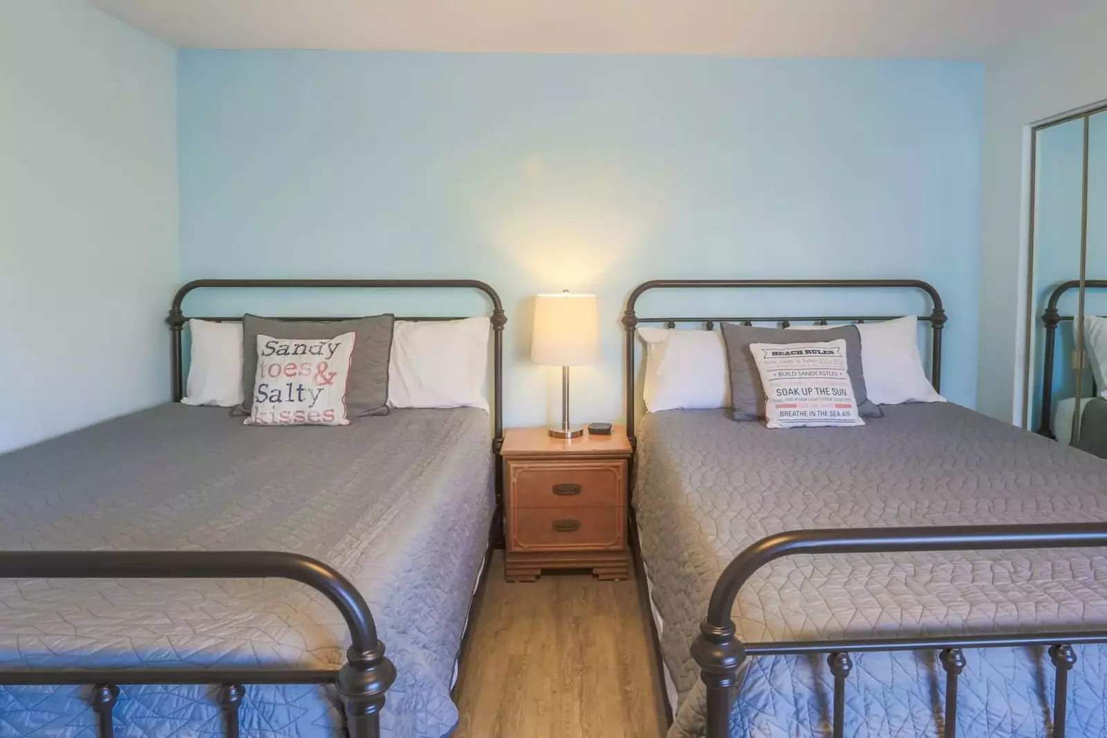 A nightstand with a reading lamp separates the two beds.
