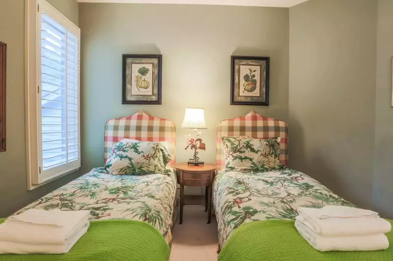 This bedroom features two twin beds and a nightstand with reading lamp.