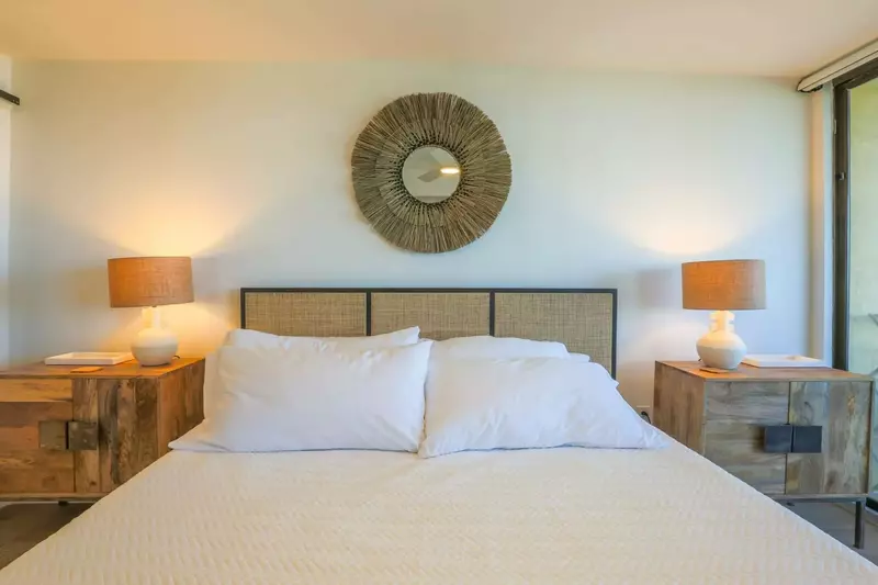 The master suite has a king bed, nightstands with reading lamps and sliding door access to the balcony.
