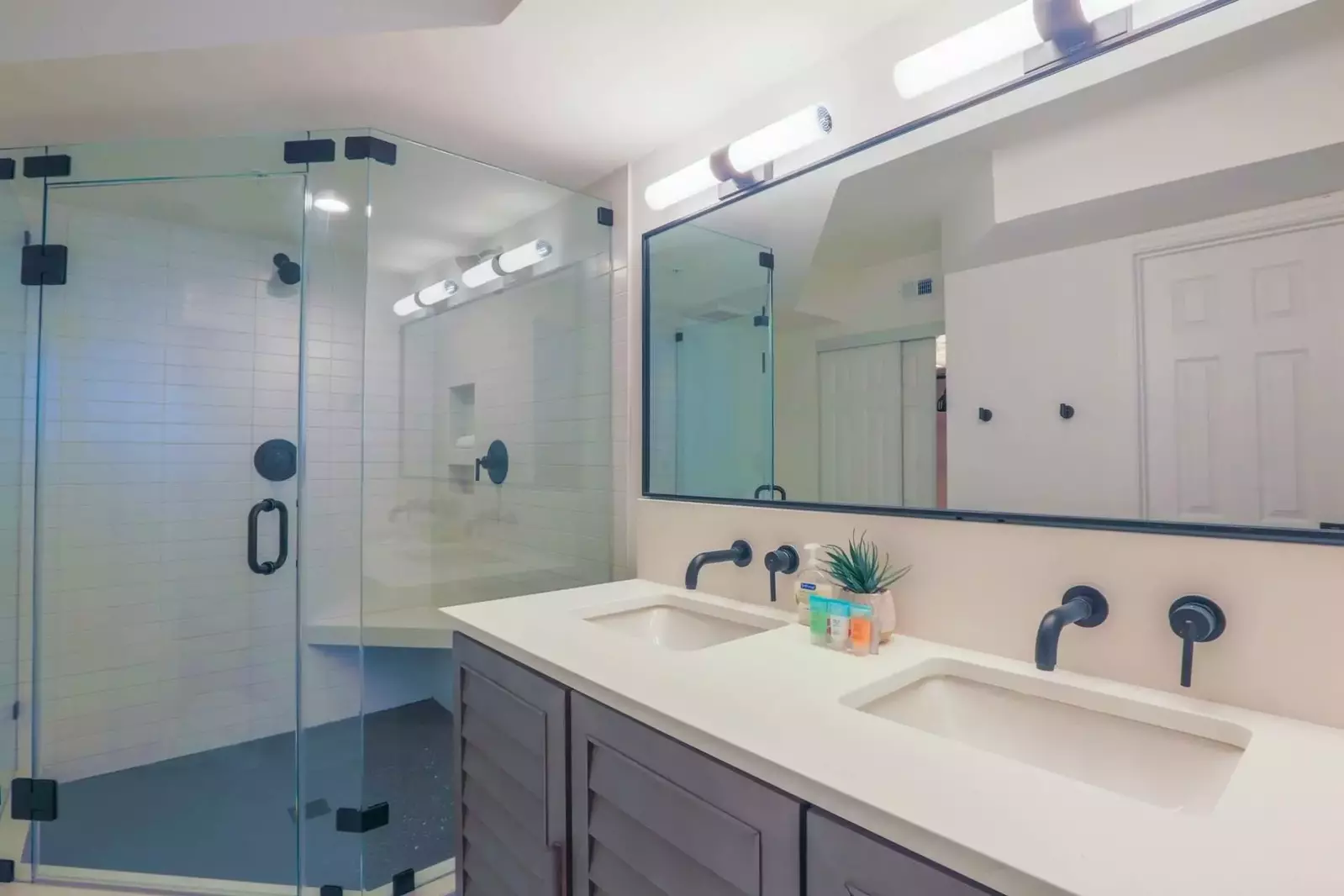 This master bathroom features a spacious, tiled walk-in shower and a double sink vanity.
