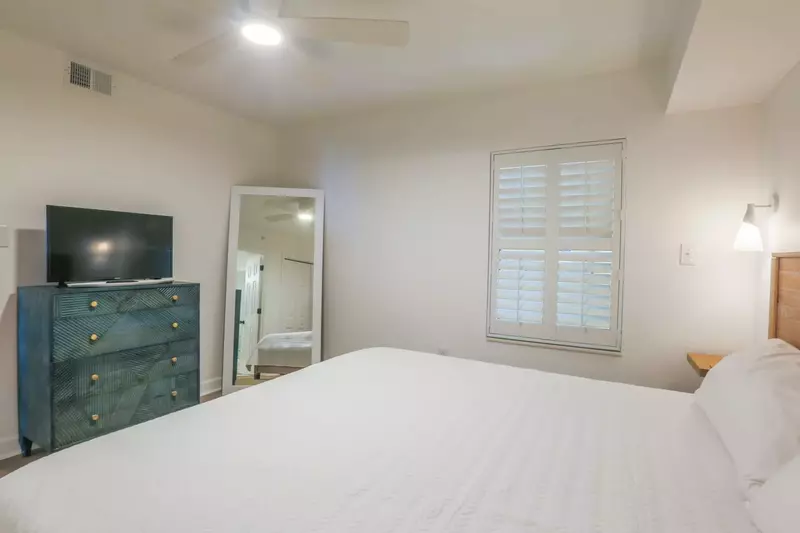 This second master suite also has a ceiling fan, dresser with smart TV and a floor mirror.