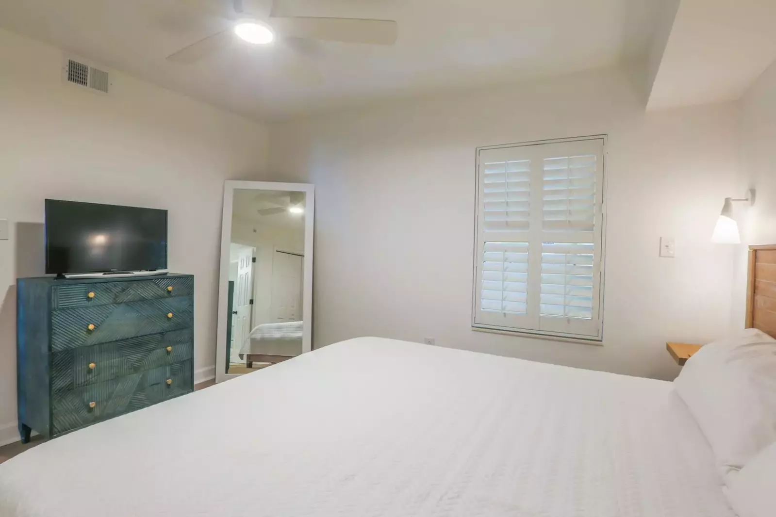 This second master suite also has a ceiling fan, dresser with smart TV and a floor mirror.