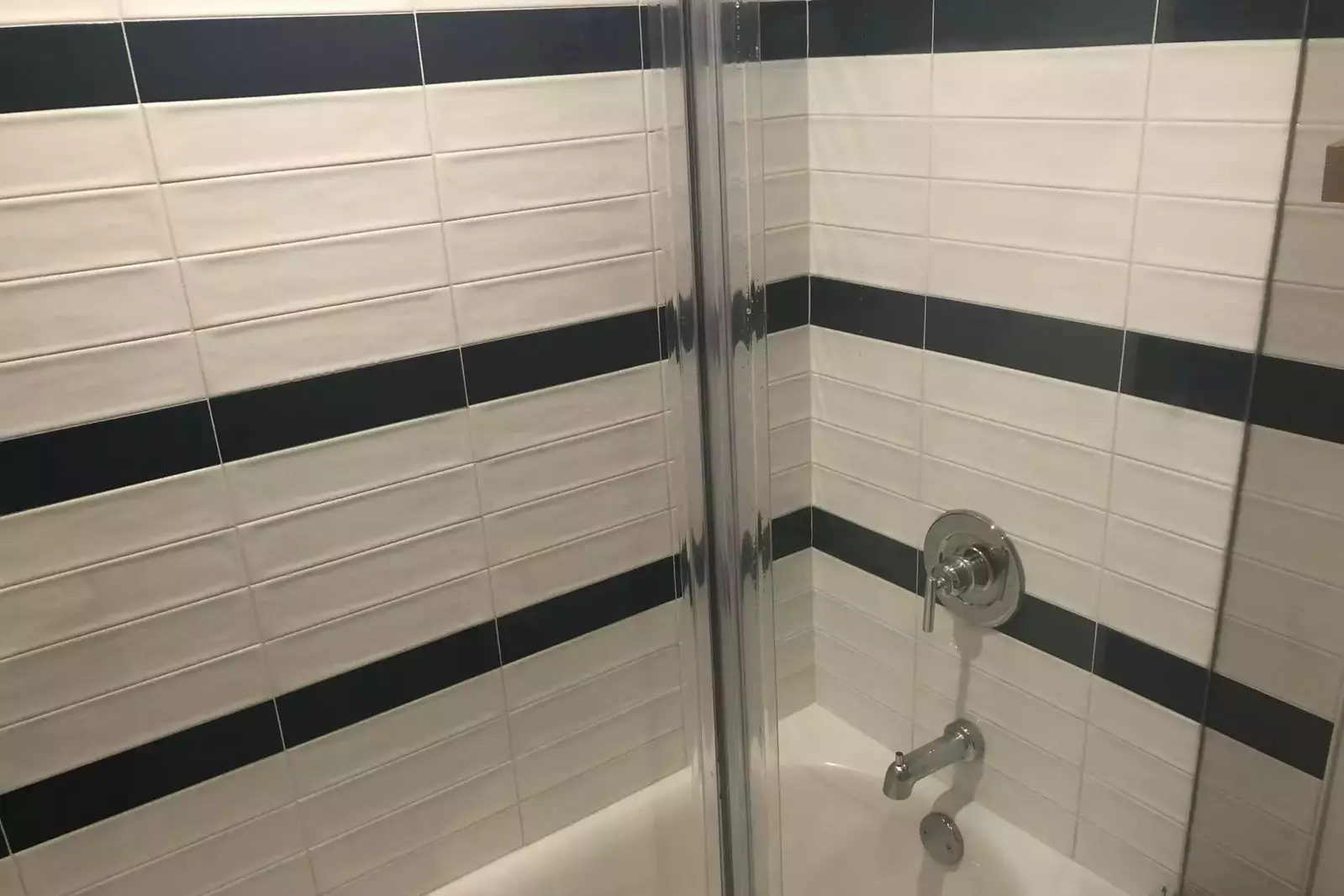 The shower/tub combo features beautiful white and navy tile.
