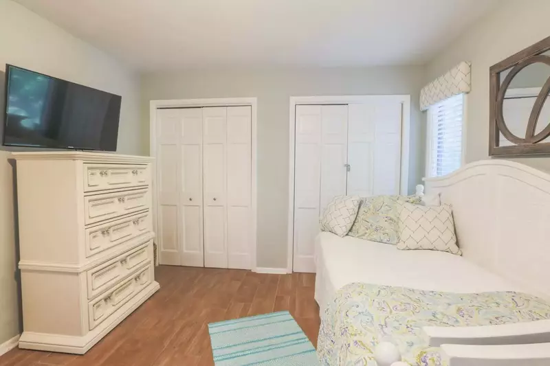 This bedroom also has a dresser and a mounted, large screen TV.