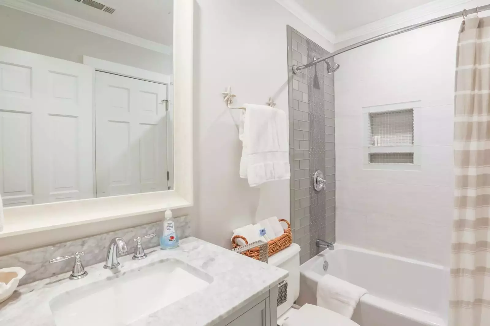 This renovated bathroom is accessed from the hallway and has a tiled shower/tub combo.