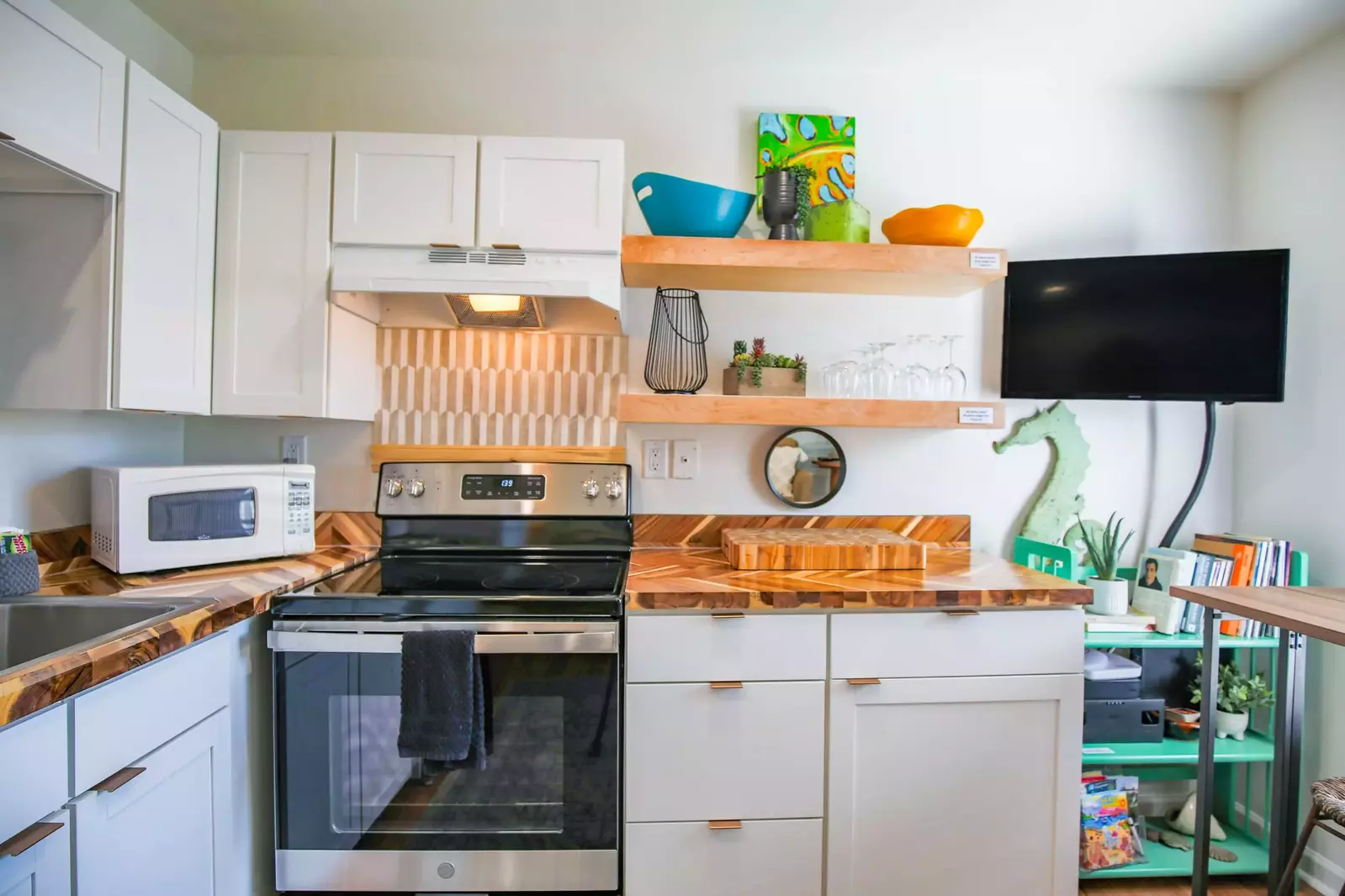 There is a wall-mounted smart TV in the kitchen and dining area.