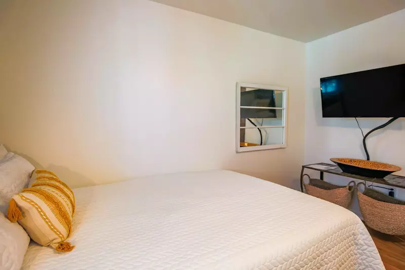 There is a wall-mounted smart TV at the foot of the bed.