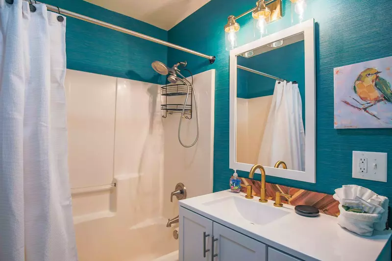The bathroom features a shower/tub combo, new wallpaper and a new vanity.
