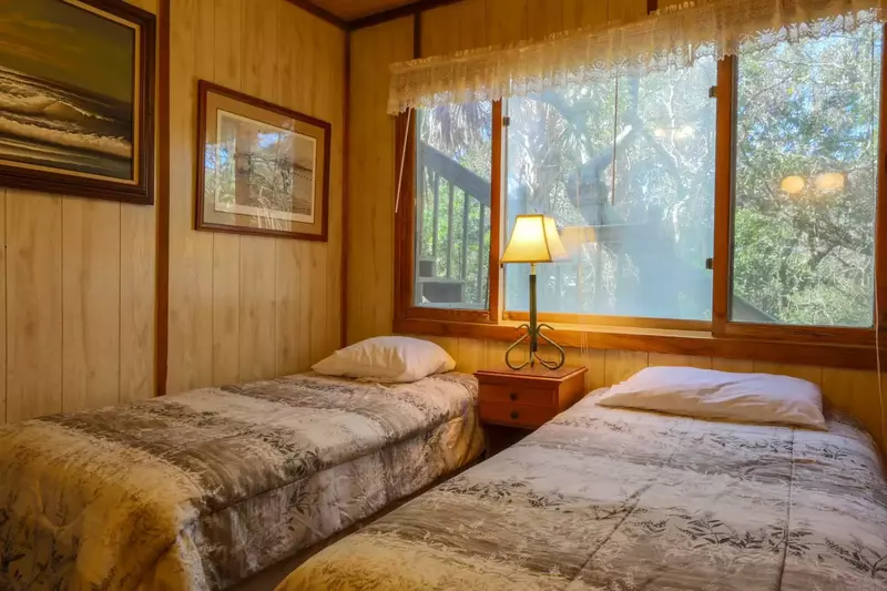 The guest bedroom has two twin-sized beds, a dresser and a nightstand with reading lamp.