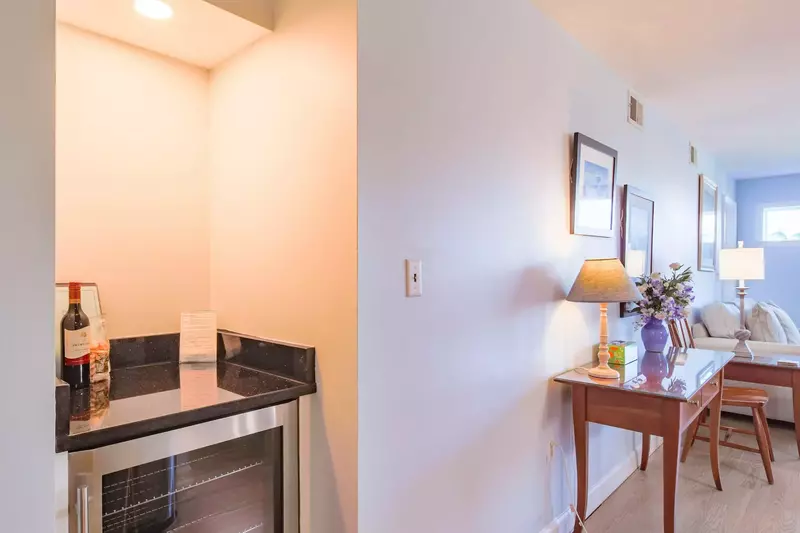 There's a small drink refrigerator and countertop near the dining table and living room.