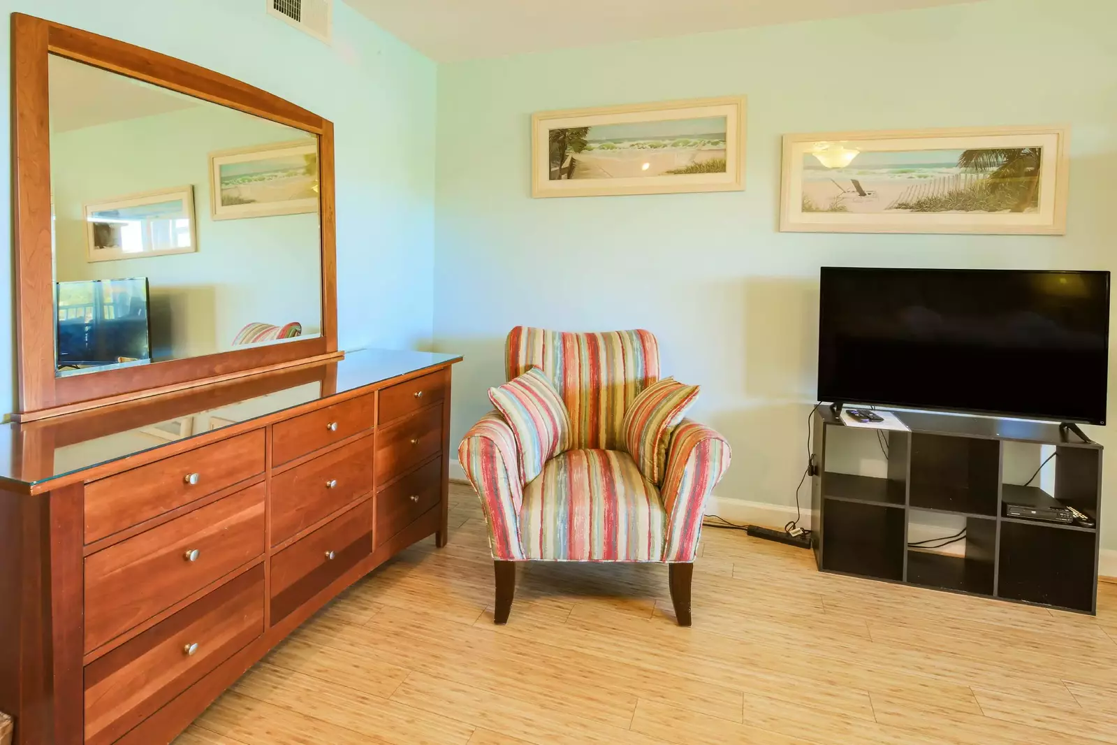 There is an arm chair in the master suite near the dresser and smart TV.