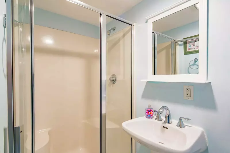 The en-suite bathroom has a walk-in shower and pedestal sink.