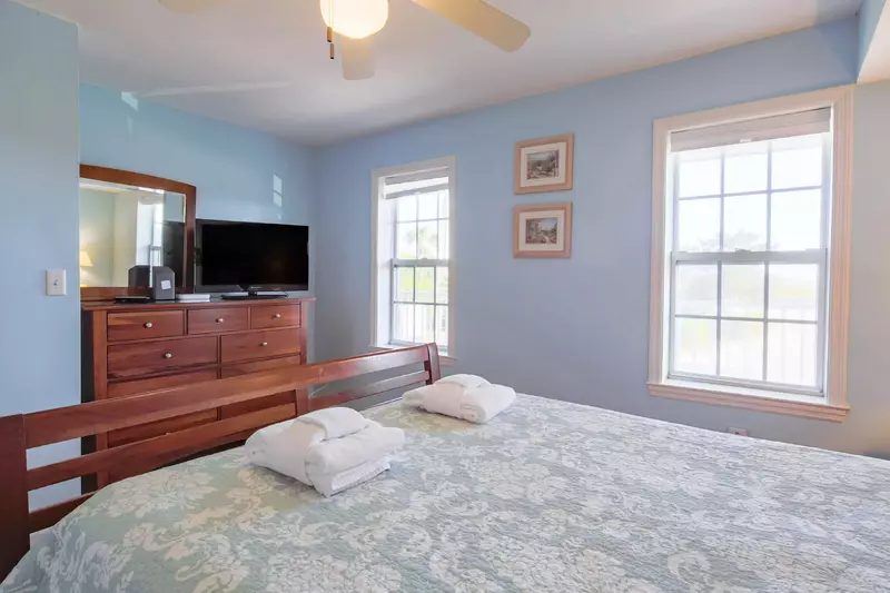 This guest bedroom also has a dresser, ceiling fan and smart TV.