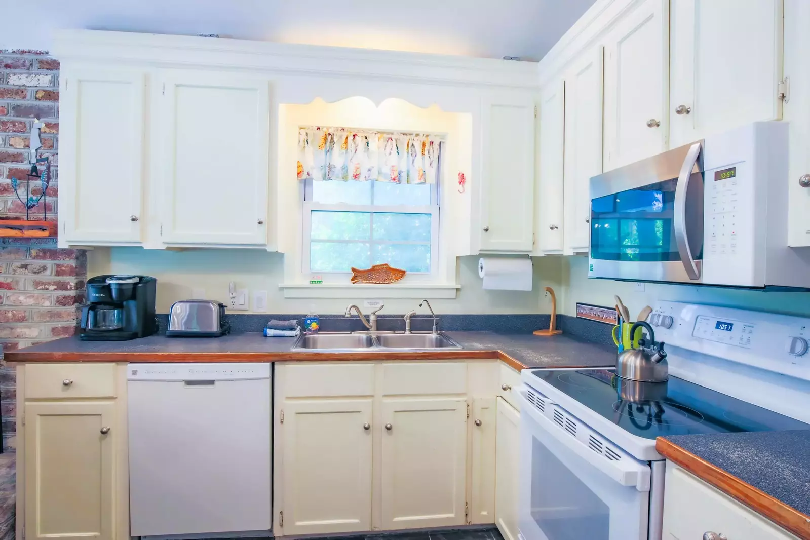 The kitchen features a dishwasher, stove, sink, coffee maker & mircrowave.