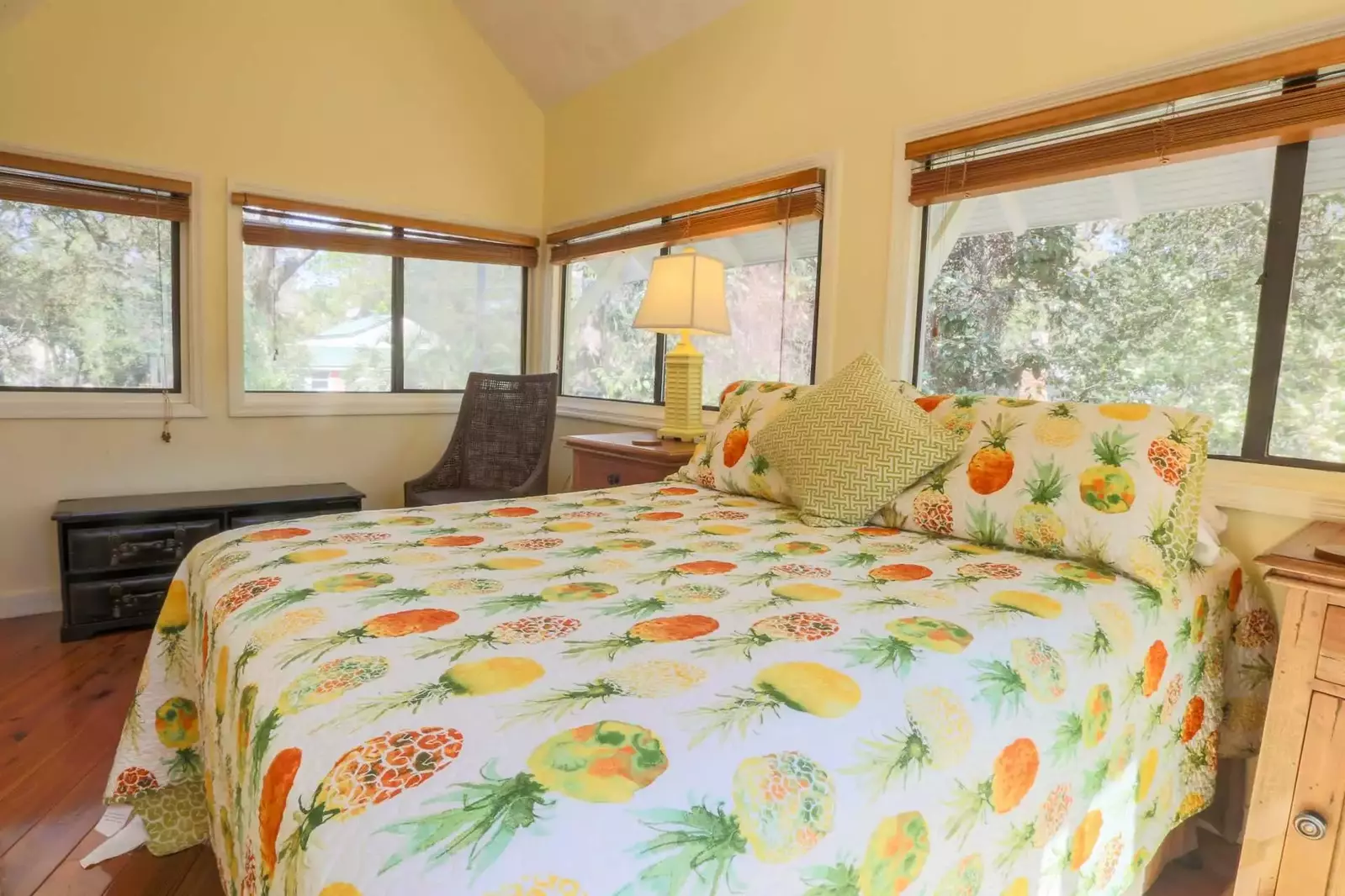 This bright & cheery guest bedroom has three walls of windows & sliding glass doors.