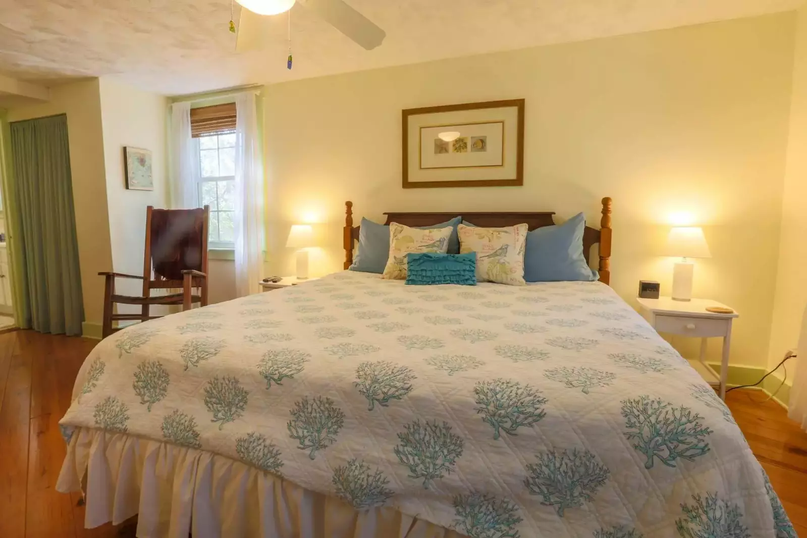 The master bedroom features a king-sized bed, night stands with reading lamps & a rocking chair.