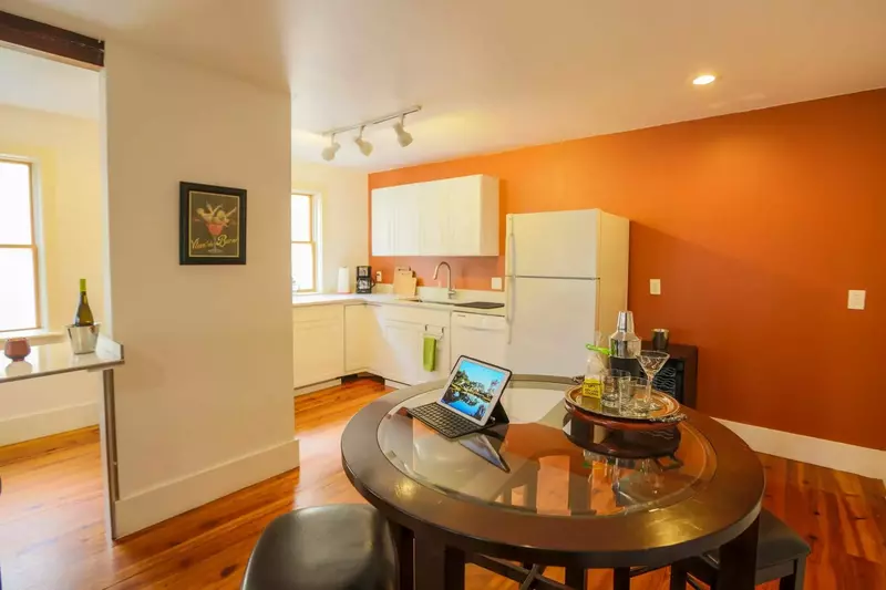 There is also a dining table with four stools near the kitchen.