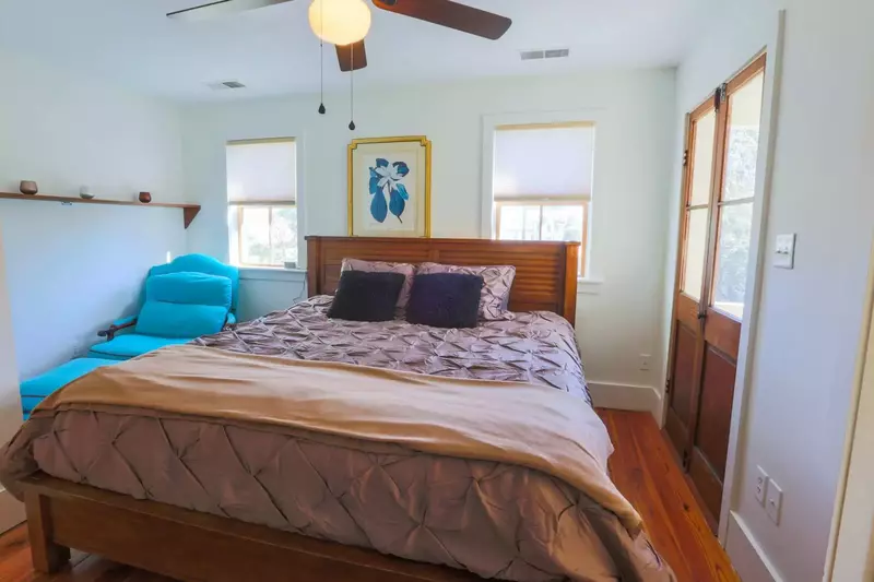 This bedroom features a king bed, arm chair and ceiling fan.
