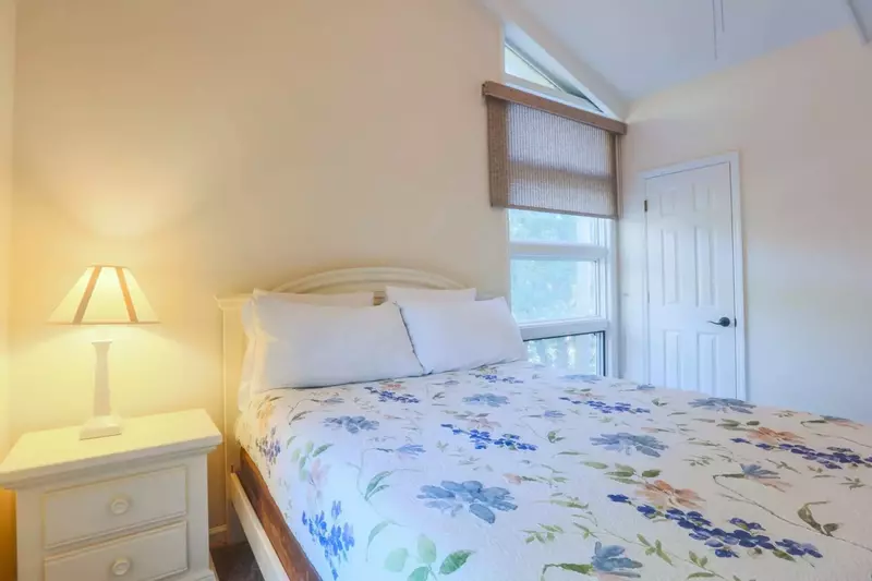 This guest bedroom features a queen bed and nightstand with a reading lamp.