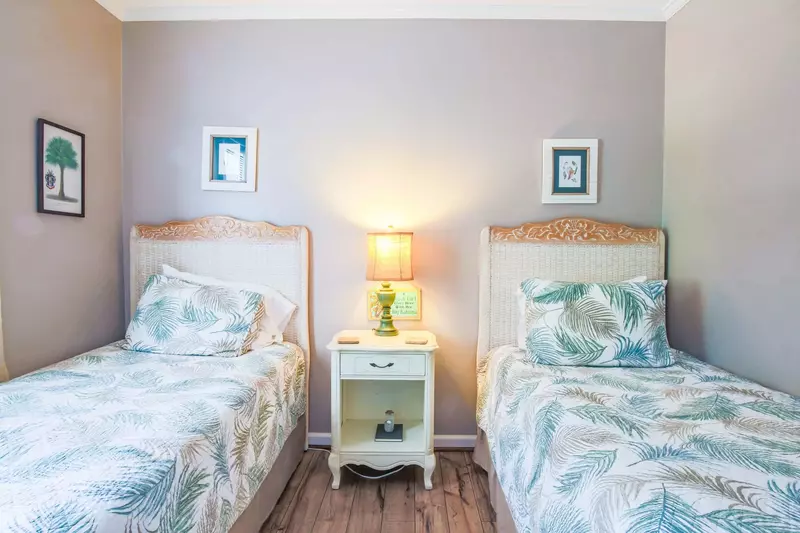 This guest bedroom contains two twin beds, a dresser and nightstand.