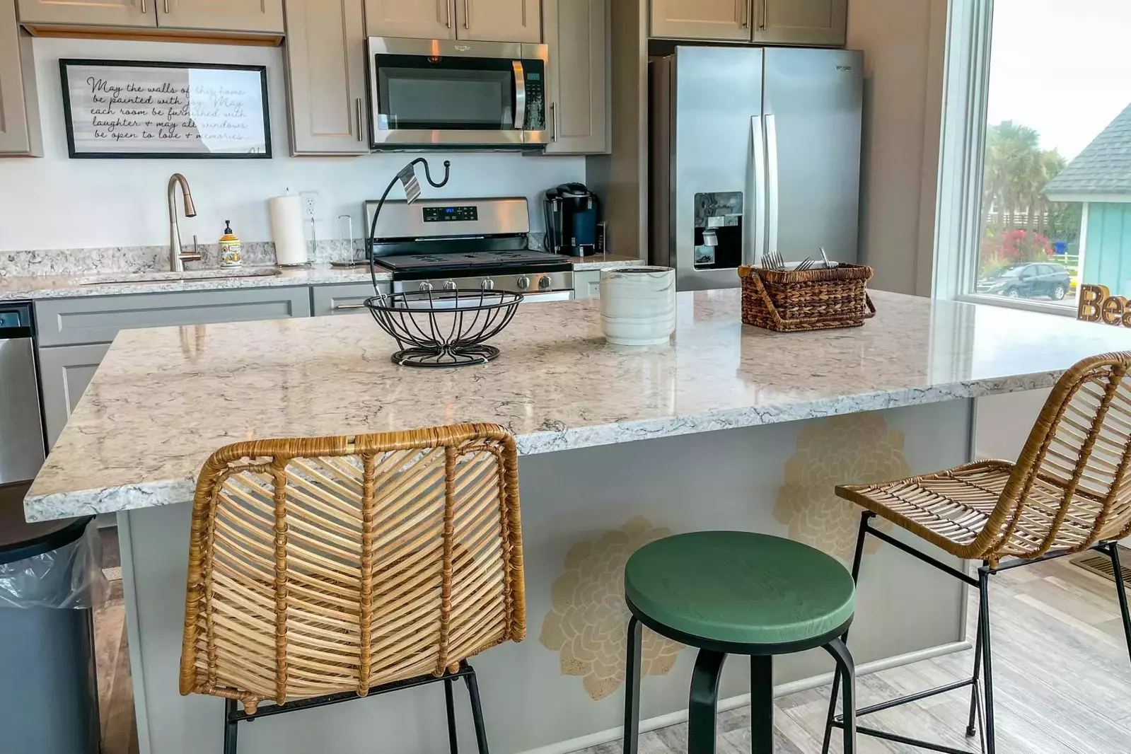 The kitchen features a central island (with 3 stools), stainless steel appliances and gray cabinets.