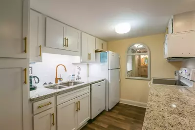 This gorgeous kitchen features white cabinetry, granite countertops and new flooring.