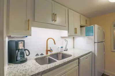 The kitchen also features white appliances and a white tiled backsplash.