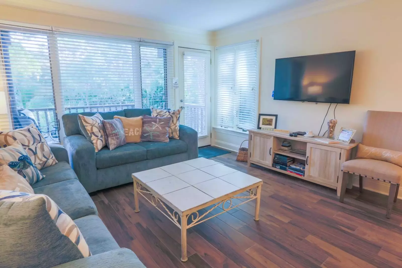 The living room has a mounted large screen streaming TV and doorway to the private back porch.