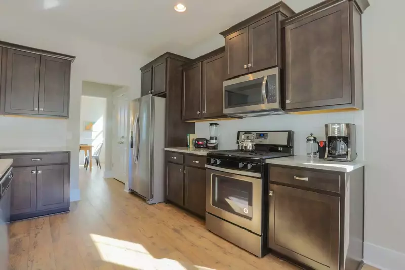 The kitchen features stainless steel appliances, white subway tiled back splash and dark brown cabinetry.
