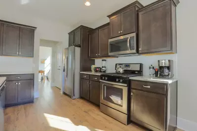 The kitchen features stainless steel appliances, white subway tiled back splash and dark brown cabinetry.