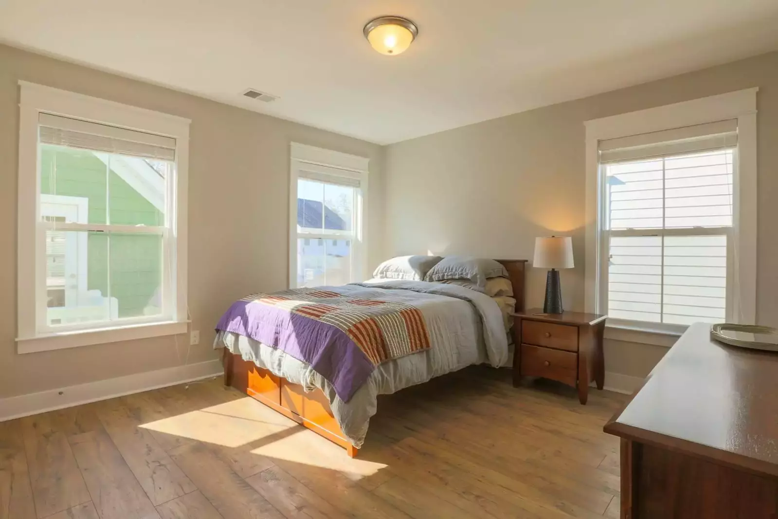 This guest bedroom features a queen-sized bed, dresser and nightstand with reading lamp.