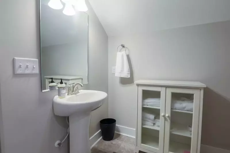 The third floor bathroom has a walk-in shower, toilet, sink and storage cabinet.