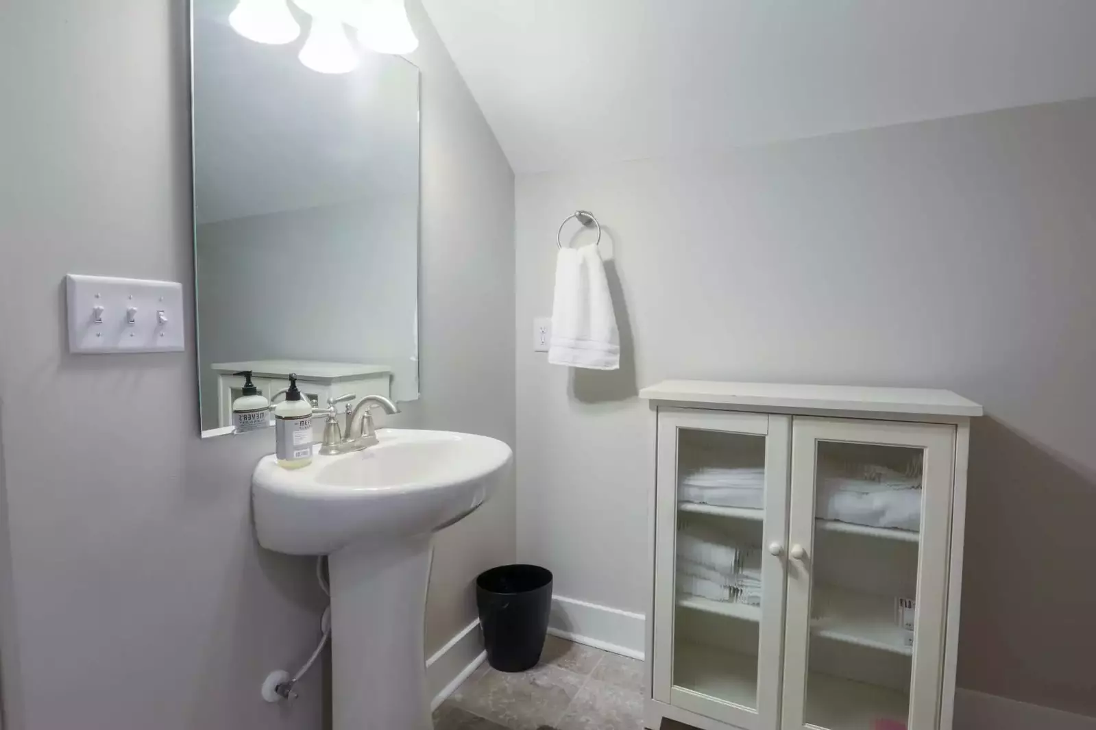 The third floor bathroom has a walk-in shower, toilet, sink and storage cabinet.