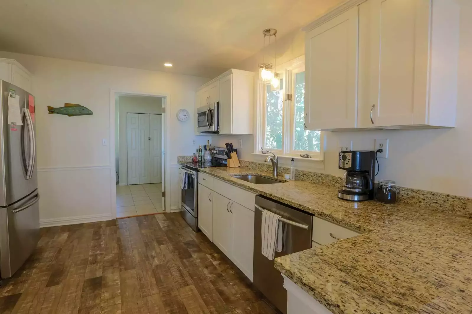 The kitchen features stainless steel appliances, white cabinetry and granite countertops.