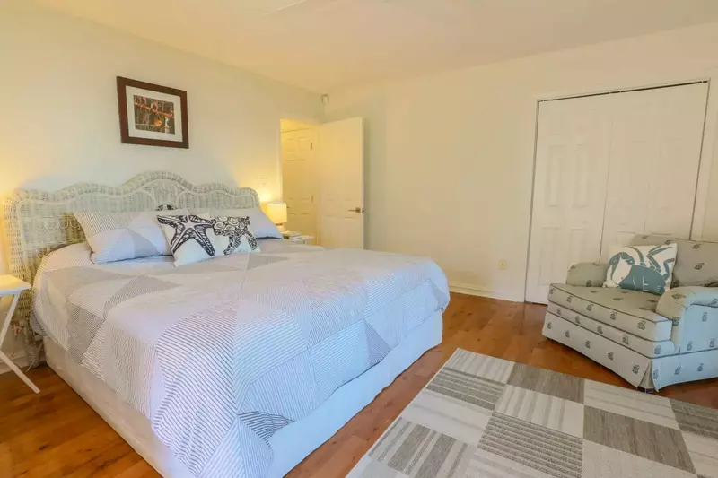 The master bedroom also has an overstuffed arm chair, closet and hardwood floors.