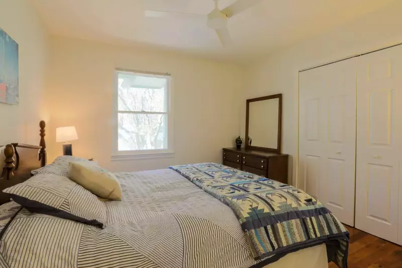 This guest bedroom features a queen bed, dresser, ceiling fan and nighstand with reading lamp.