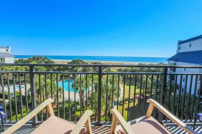 The private balcony off of the living room features glorious views of the ocean, beach, sand dunes & community pool.