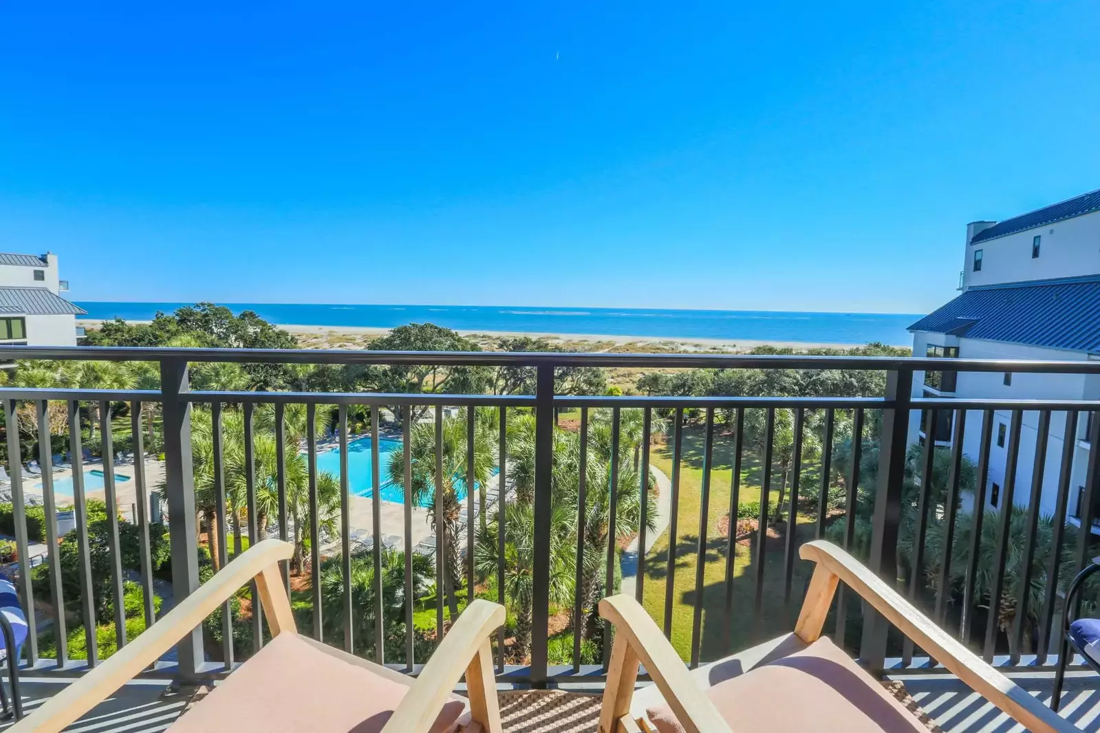 The private balcony off of the living room features glorious views of the ocean, beach, sand dunes & community pool.