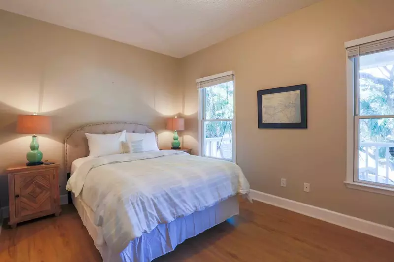 This guest bedroom features a queen bed, ceiling fan and nighstands with reading lamps.