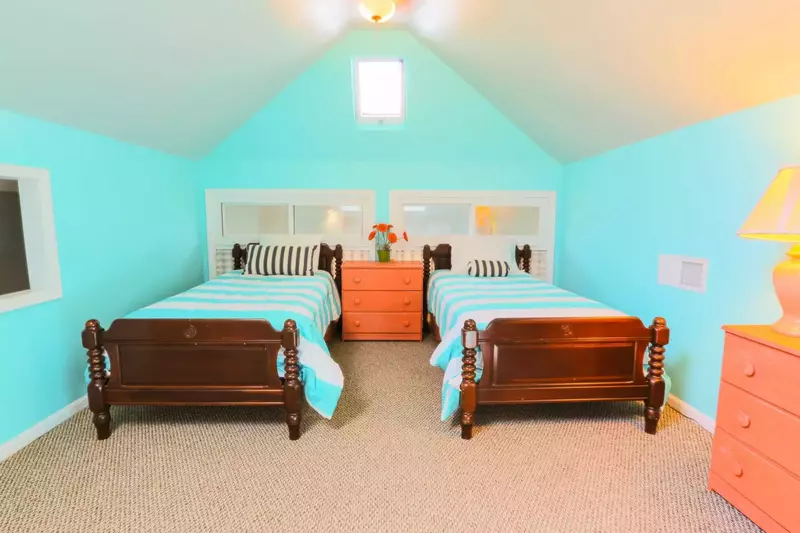 The loft bedroom has 3 twin sized beds, 2 dressers and ceiling fans.
