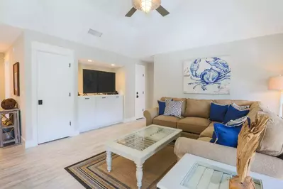 The living room features a spacious sectional couch, a large screen cable TV and a vaulted ceiling with ceiling fan.