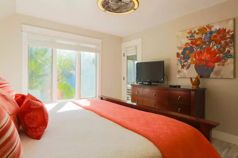 The master bedroom features cable TV, a ceiling fan and access to the screened porch.