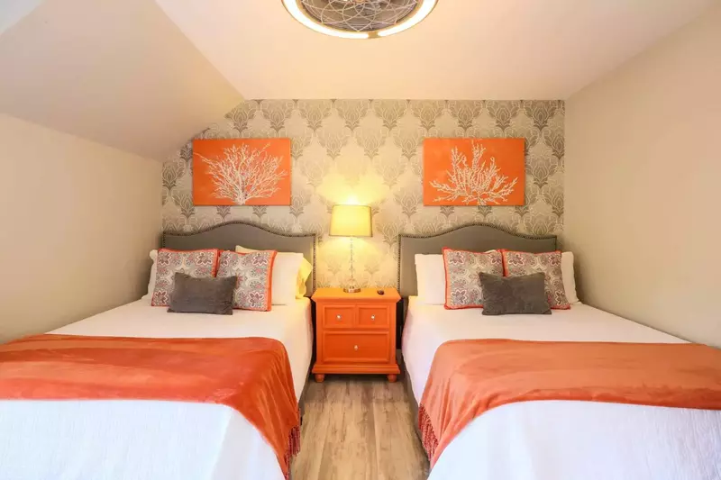 The guest bedroom features two full size beds, a ceiling fan and night stand with reading lamp.