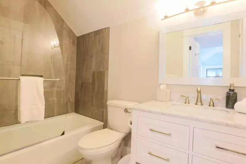 The guest bathroom has a large vanity and a tiled tub/shower combo.