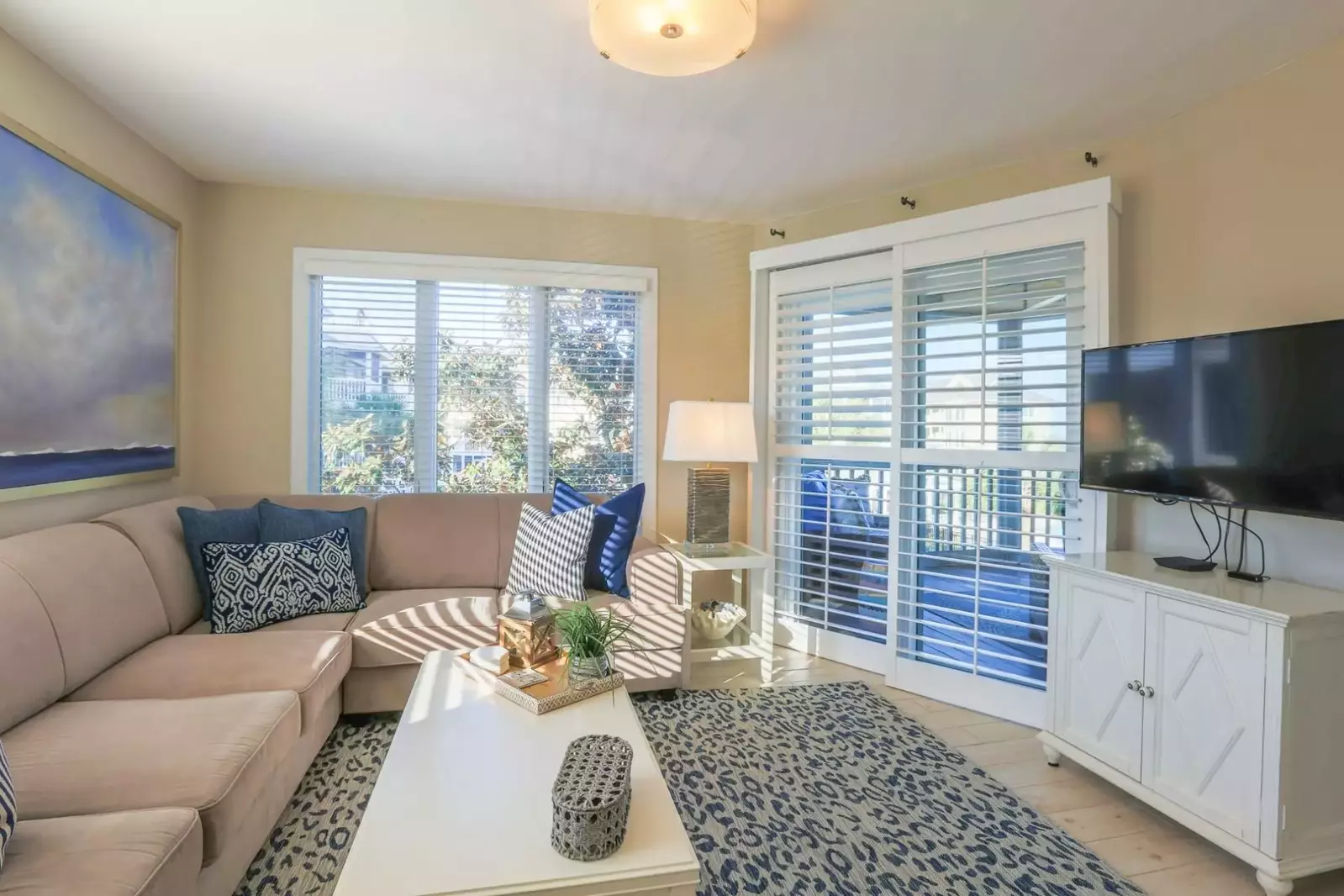 The living room features a spacious sectional couch and a large screen cable TV.