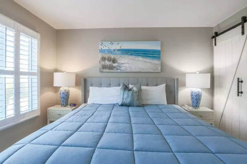 The master bedroom features a king size bed, night stands with reading lamps and a ceiling fan.