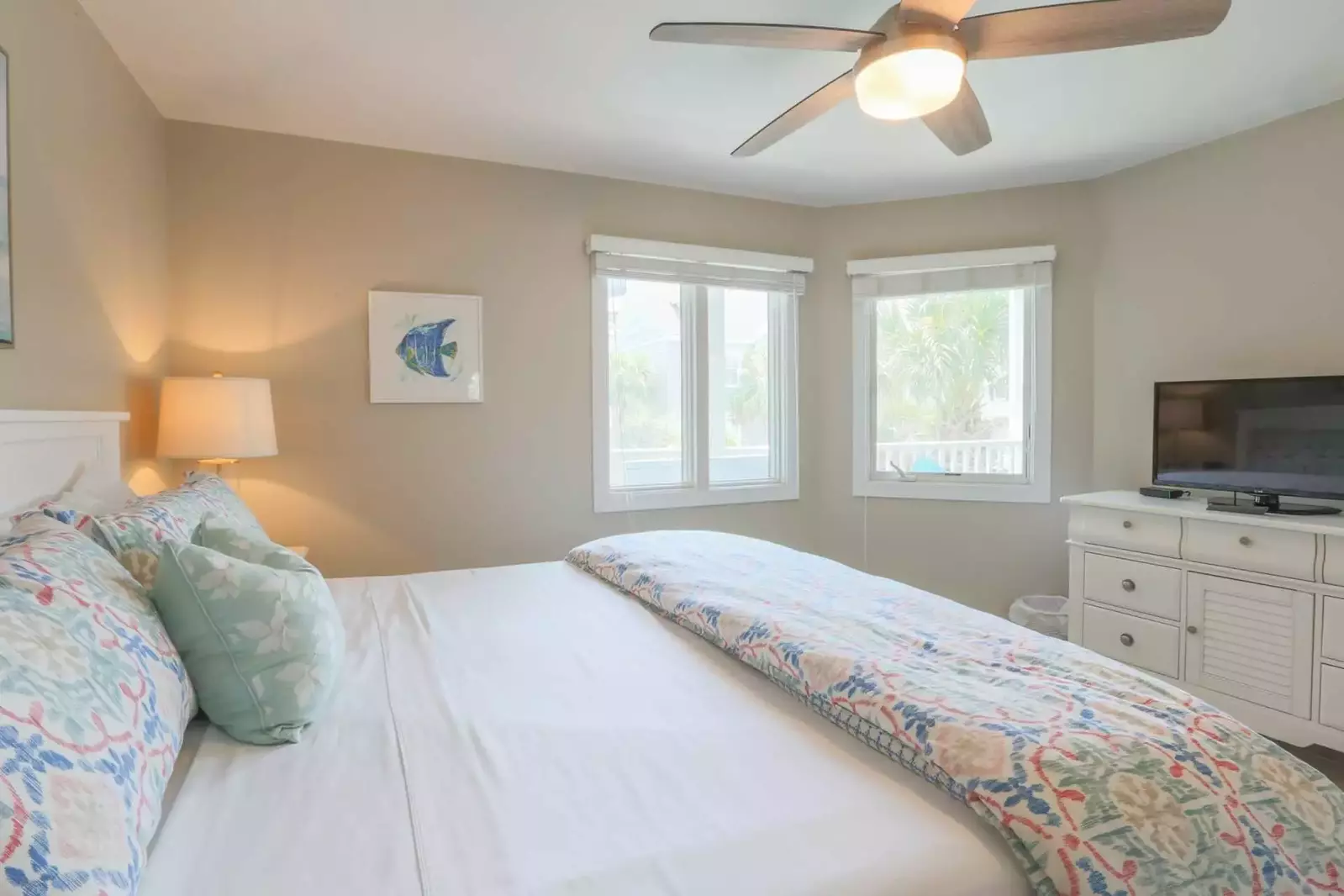 The guest bedroom has a dresser with cable TV, ceiling fan and en suite bathroom.