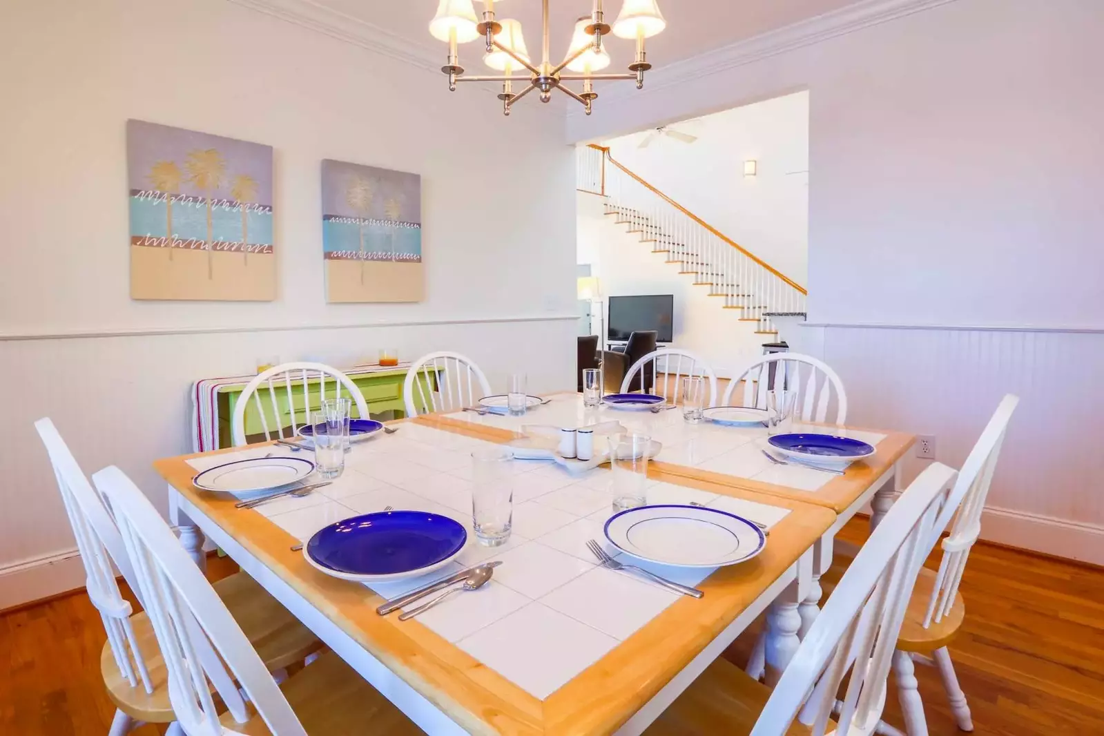 The dining room features beadboard paneling, wood floors, dining table & chairs and a sideboard table.